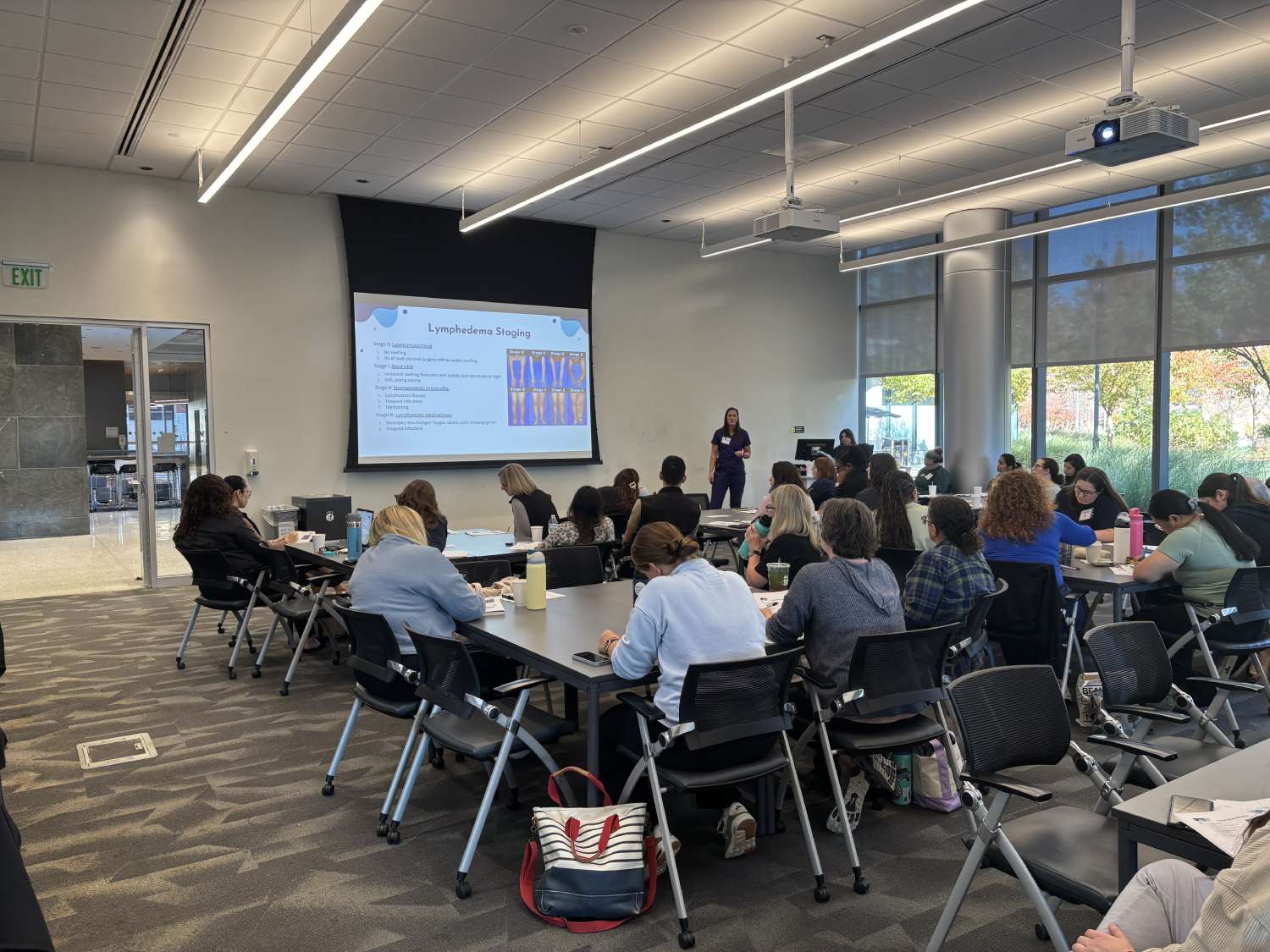 Participants sitting at tables in groups as lymphedema staging is presented